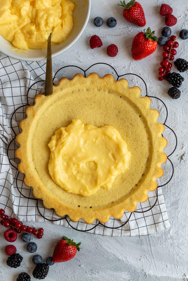 Obstkuchenboden wird mit Eierlikörpudding bestrichen. #Pudding #Eierlikör #Beeren #Kuchenboden #Bisquitboden