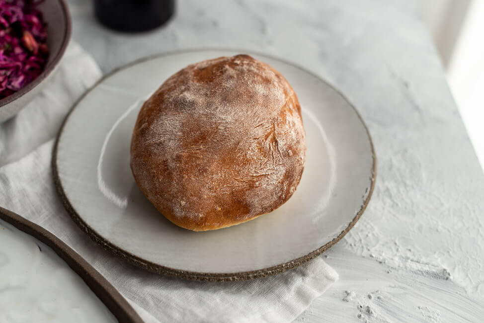 Brioche Burger Bun auf hellgrauem Keramikteller.
