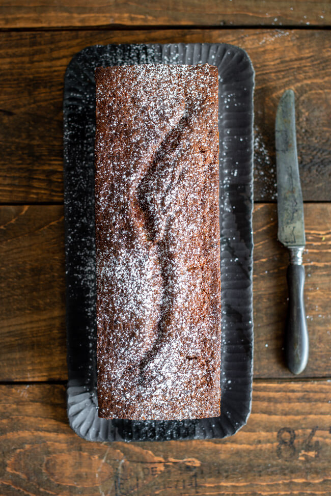 Bananenbrot mit Schokolade auf schwarzer Kuchenplatte.