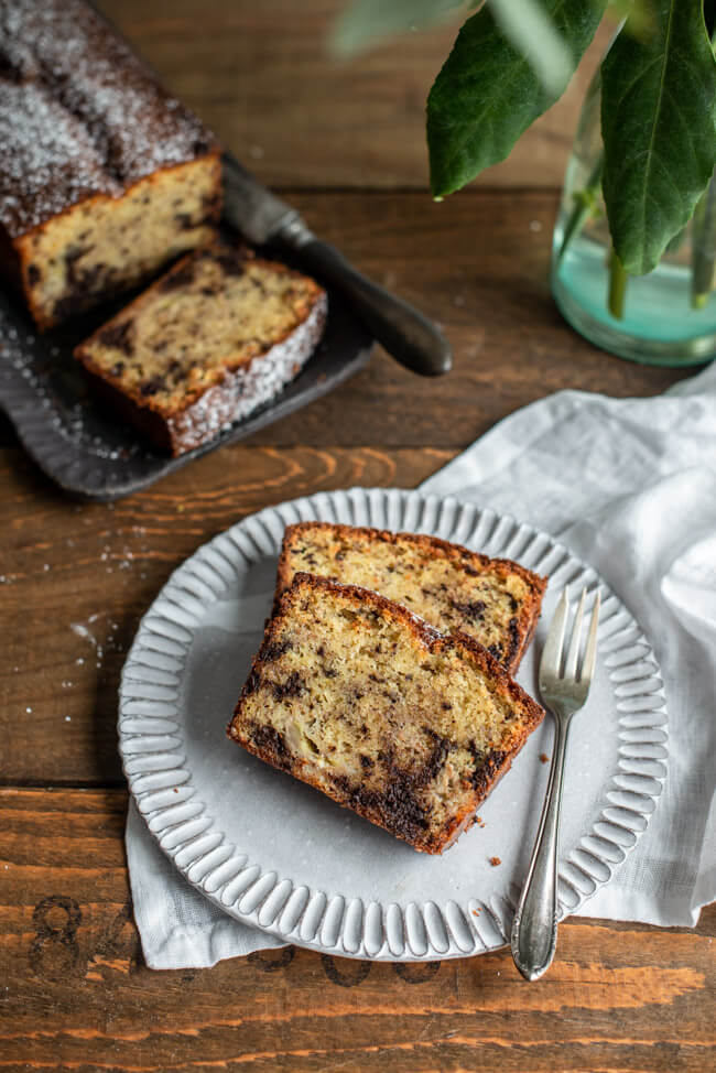 Bananenbrot mit Schokolade auf weißem Keramikteller.