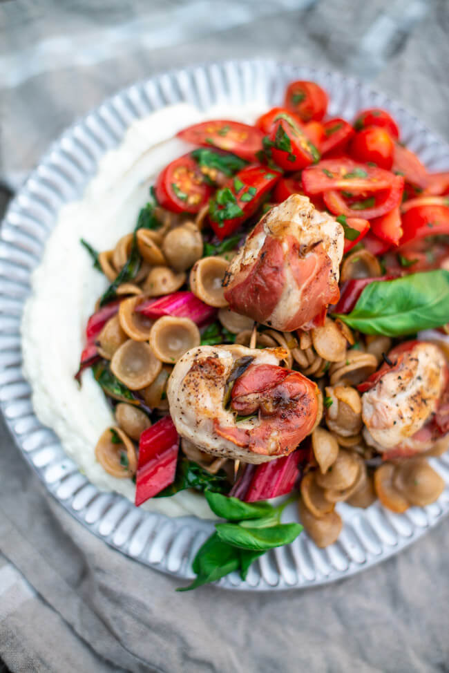 Saltimbocca-Röllchen aus Hähnchenbrustfilet mit Orecchiette und Mangold. Dazu cremiger Ricotta und Tomatensalat mit Basilikum.