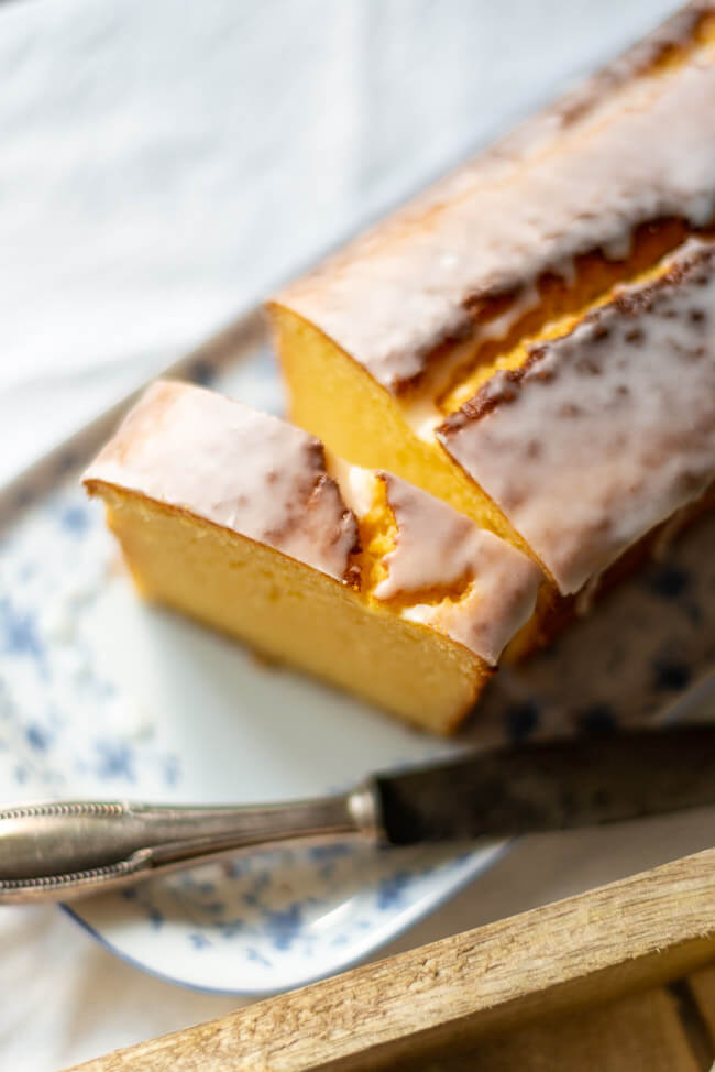 Zitronenkuchen, angeschnitten auf blau-weißer Kuchenplatte.
