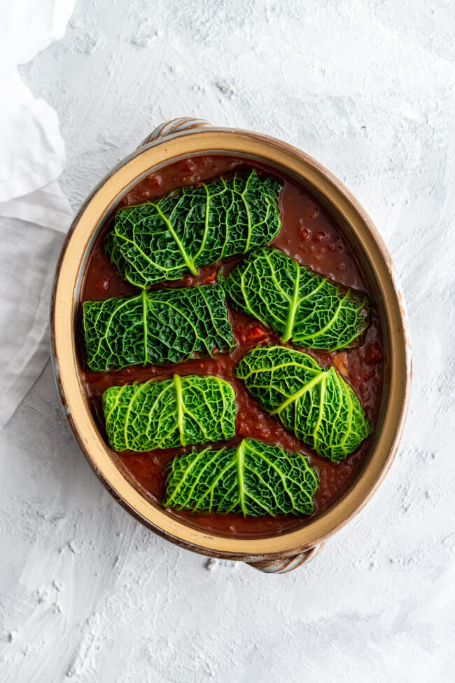 Vegetarische Wirsingrouladen in Tomatensauce in rustikaler Tonauflaufform.