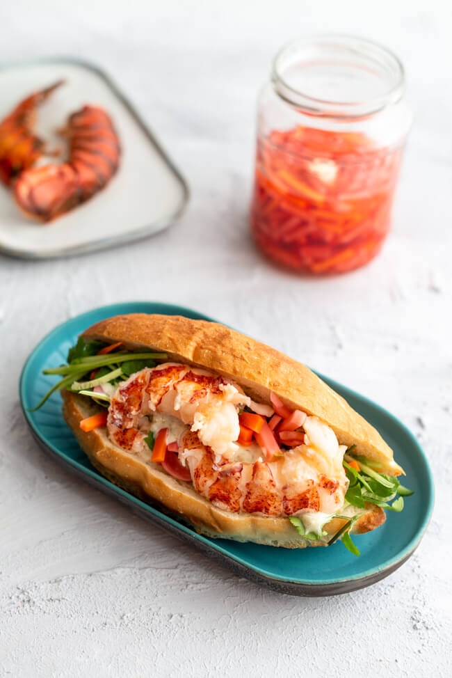 Banh Mi mit gebratenem Hummer und Don Chua auf blauem Keramikteller.
