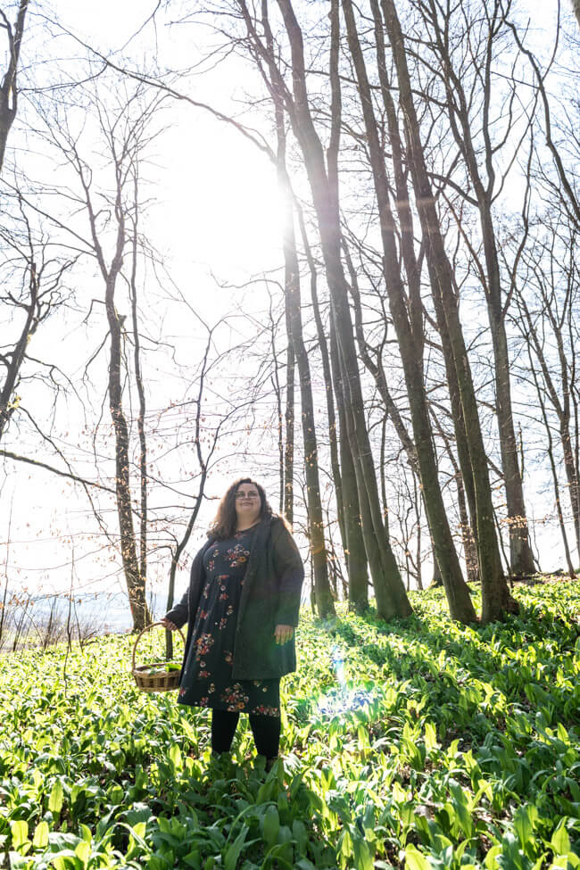 Tina von foodundco.de im Wald beim Bärlauch sammeln im Gegenlicht.