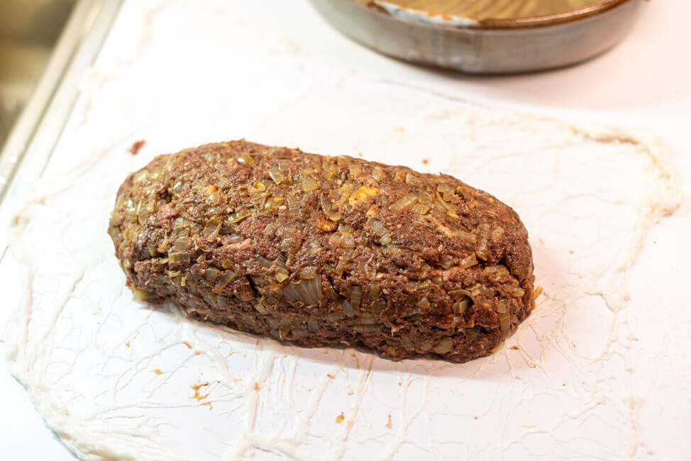 Fleischmasse für Hackbraten liegt auf Schweinenetz