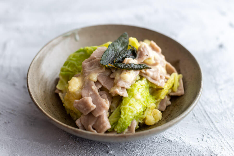 Pizzoccheri Valtellinesi - Pasta aus Buchweizenmehl mit Wirsing, Kartoffeln, Salbei, Knoblauch, brauner Butter und Käse - aus Kitchen Impossible in grauem Keramikteller auf hellem Untergrund.