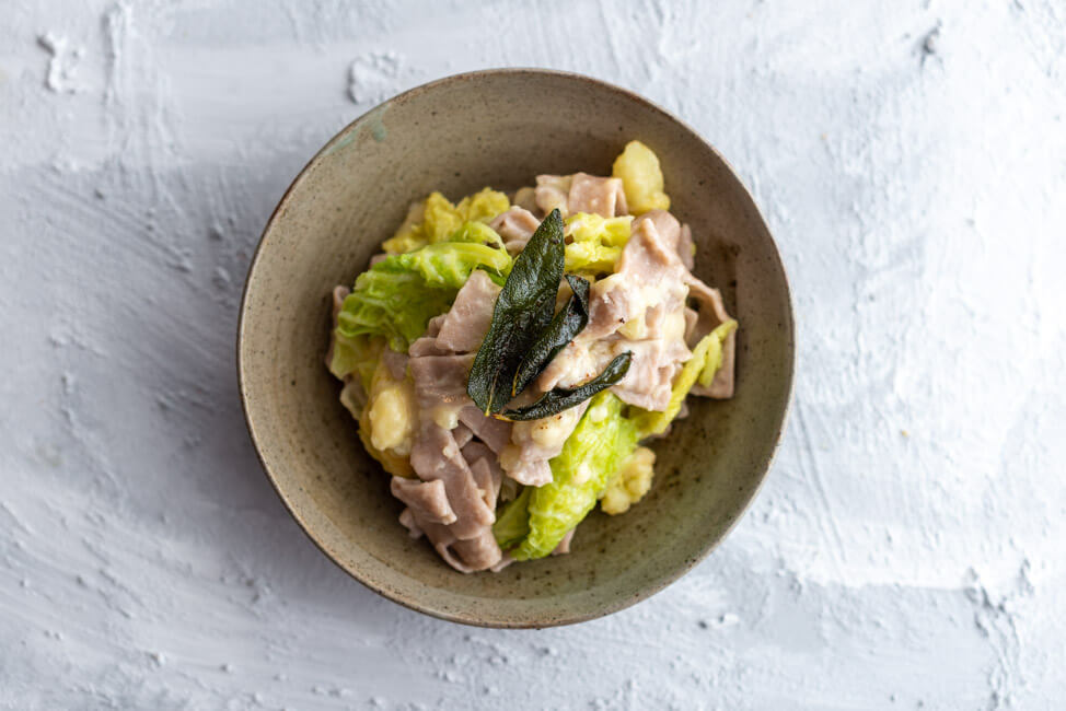 Pizzoccheri Valtellinesi - Pasta aus Buchweizenmehl mit Wirsing, Kartoffeln, Salbei, Knoblauch, brauner Butter und Käse - aus Kitchen Impossible in grauem Keramikteller auf hellem Untergrund.