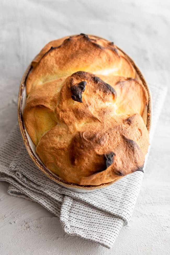 Salzburger Nockerl mit Puderzucker bestäubt aus Kitchen Impossible in Auflaufform auf hellem Untergrund.