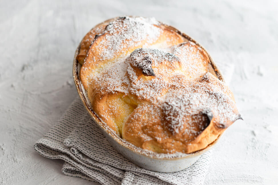 Salzburger Nockerl mit Puderzucker bestäubt aus Kitchen Impossible in Auflaufform auf hellem Untergrund.
