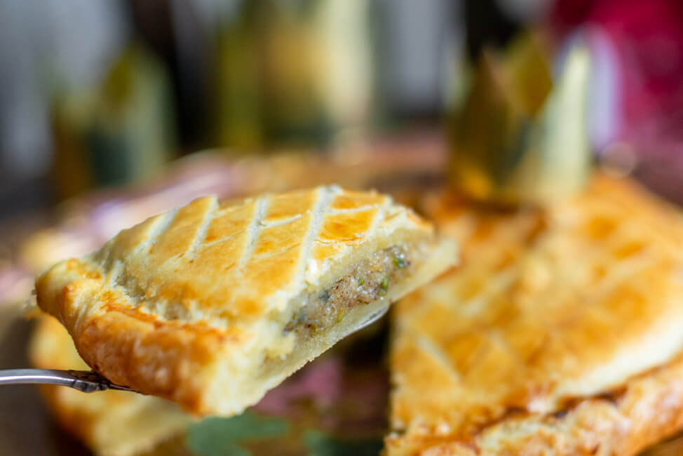 Ein Stück Galette des Rois, traditioneller Dreikönigskuchen, mit Krone auf goldenem Teller.