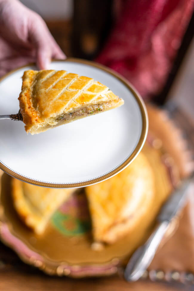 Ein Stück Galette des Rois, traditioneller Dreikönigskuchen, mit Krone auf goldenem Teller.