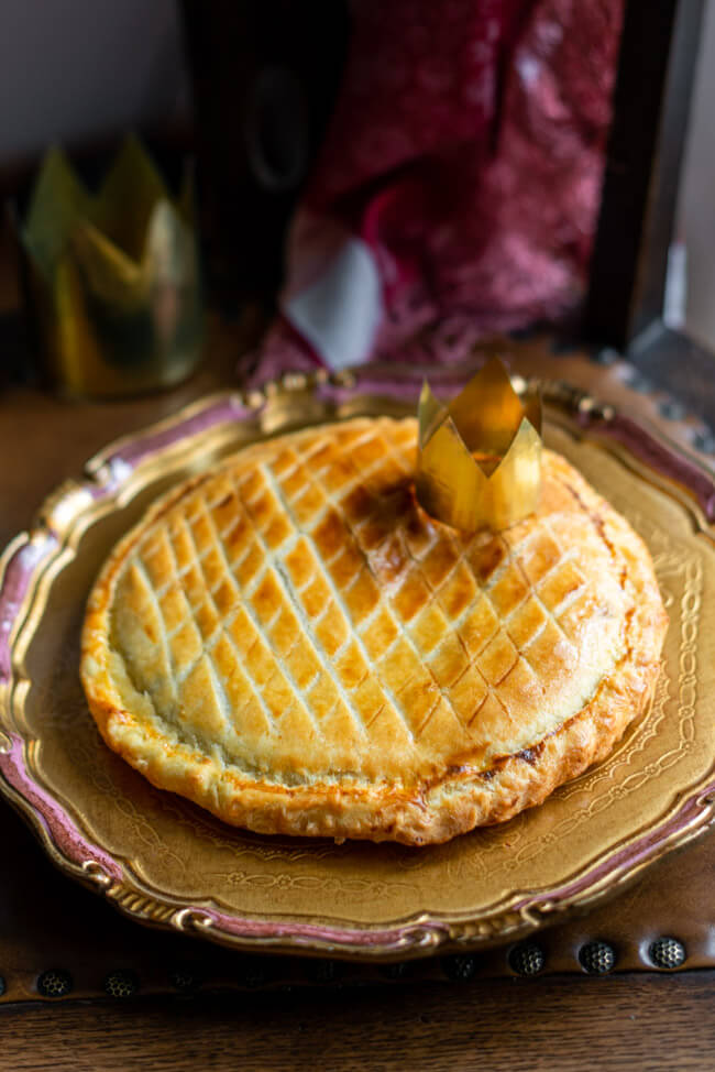 Galette des Rois, traditioneller Dreikönigskuchen mit Krone auf goldenem Teller.
