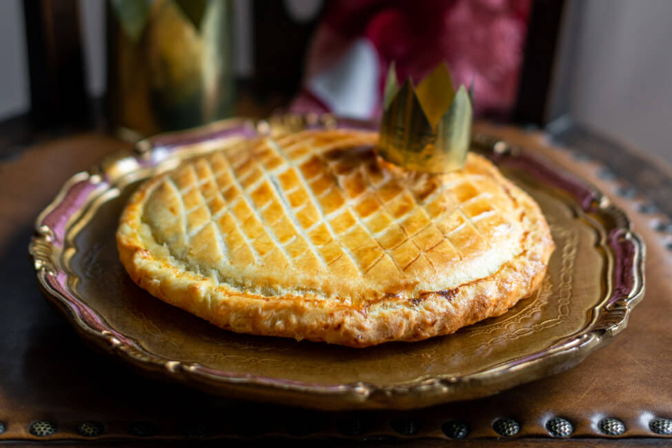 Galette des Rois, traditioneller Dreikönigskuchen mit Krone auf goldenem Teller.