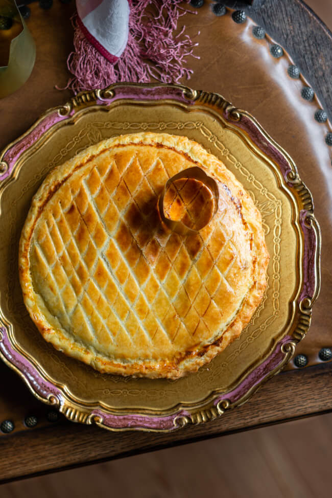 Galette des Rois, traditioneller Dreikönigskuchen mit Krone auf goldenem Teller.
