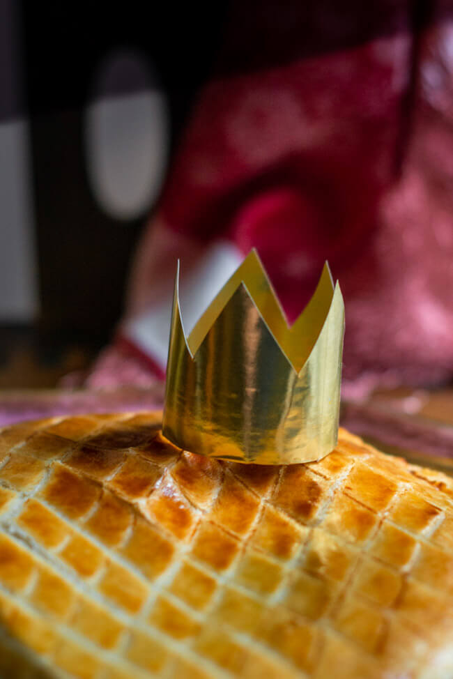 Galette des Rois, traditioneller Dreikönigskuchen mit Krone auf goldenem Teller.