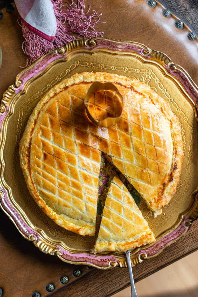 Galette des Rois, traditioneller Dreikönigskuchen mit Krone auf goldenem Teller.
