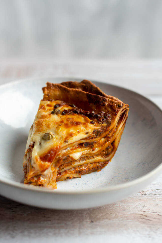 Ein Stück Vincisgrassi Lasagne auf weißem Teller.
