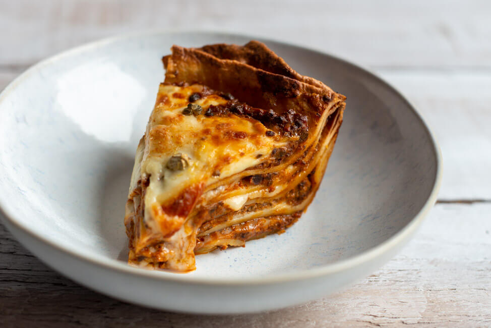 Ein Stück Vincisgrassi Lasagne auf weißem Teller.