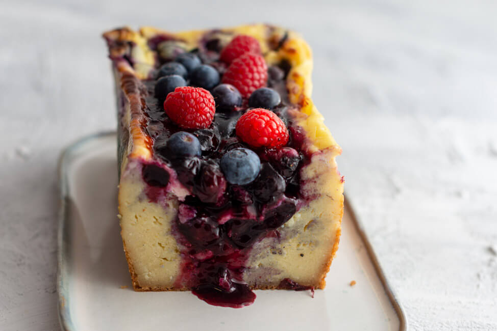 Ukrainischer Beeren-Grießkuchen angeschnitten auf hellem Untergrund.