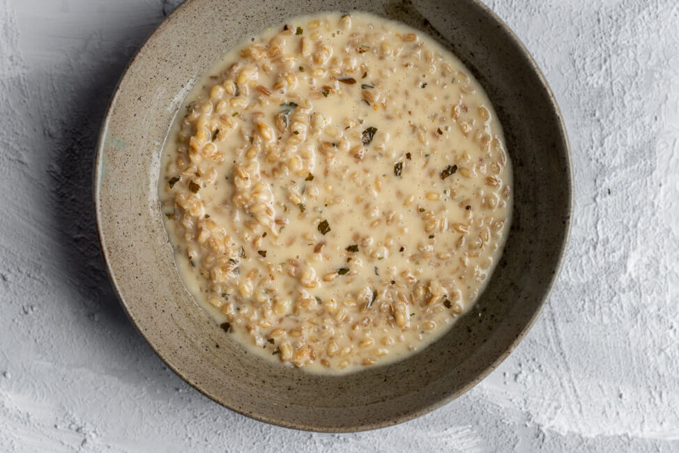 Originalrezept aus Kitchen Impossible: Orzotto in grauem Keramikteller.