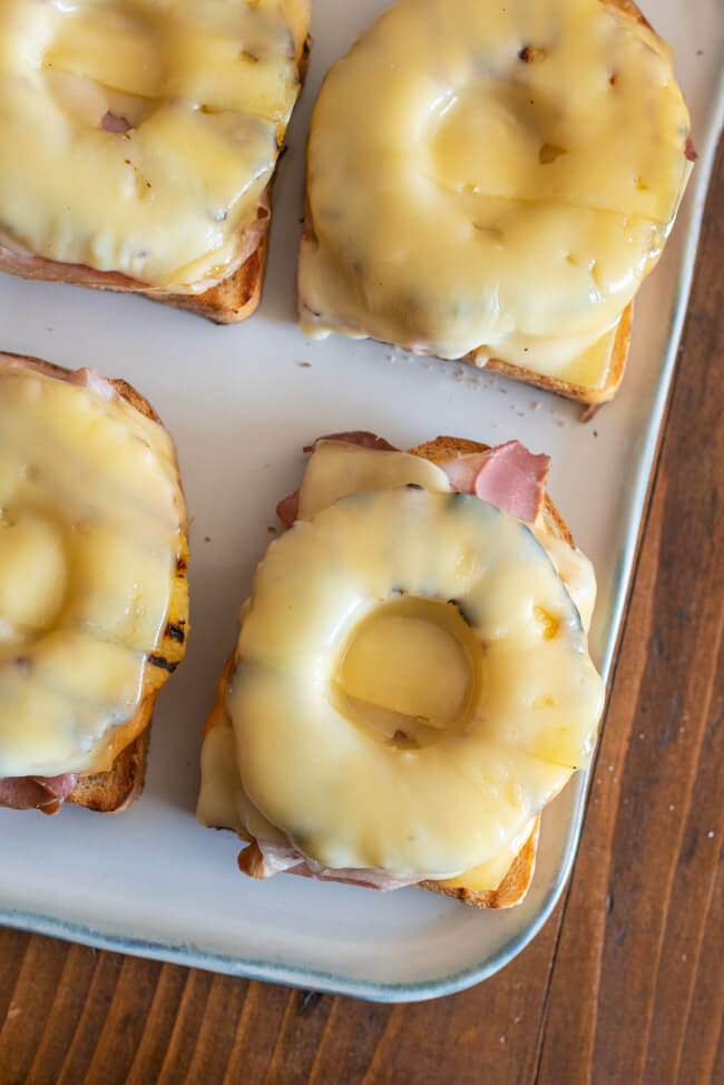 Snack-Klassiker: Toast Hawaii deluxe mit selbstgemachter Ranch-Sauce auf weißer Keramikplatte..