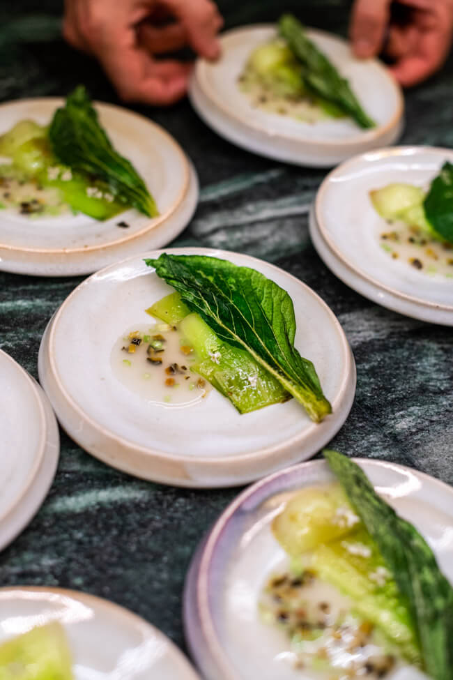 Pak Choi mit Ingwer und Chili auf weißem Keramikteller auf grüner Marmorplatte.
