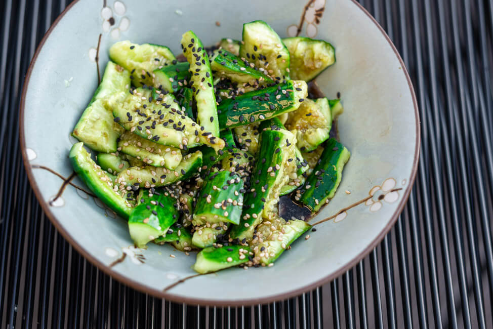 Chinesischer Gurkensalat in hellblauer Keramikschale auf schwarzem Untergrund.