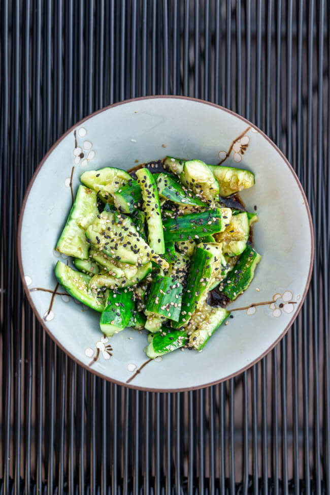 Chinesischer Gurkensalat in hellblauer Keramikschale auf schwarzem Untergrund.