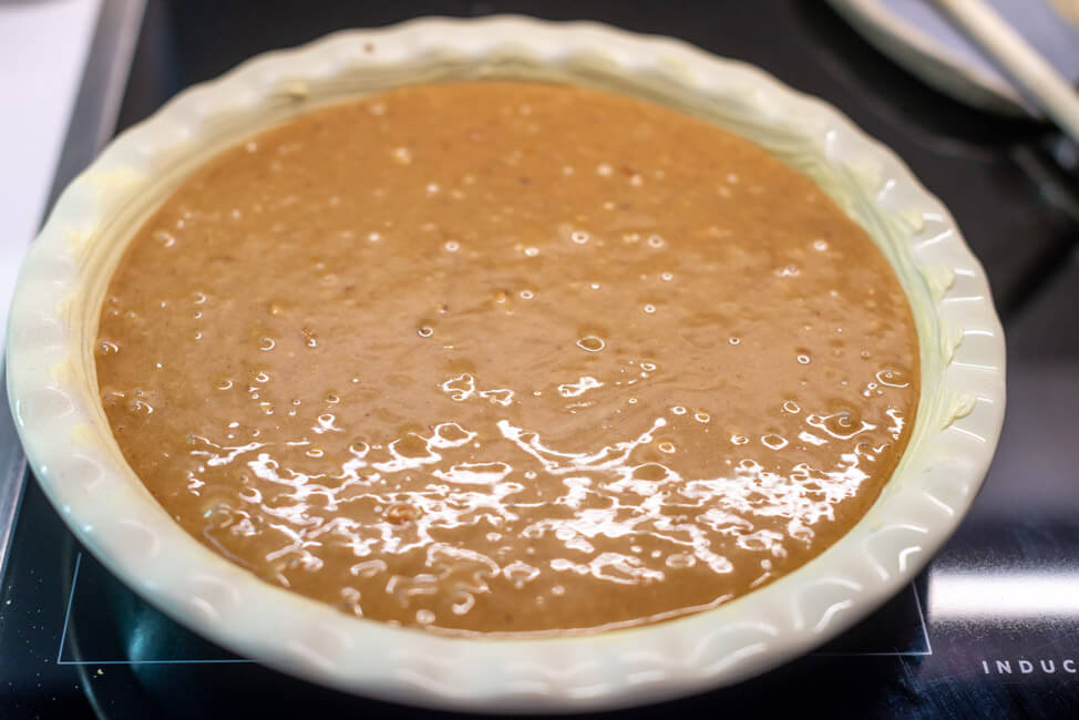Roher Teig des Zwetschgenkuchen mit Olivenöl Zimt in Pie-Form.