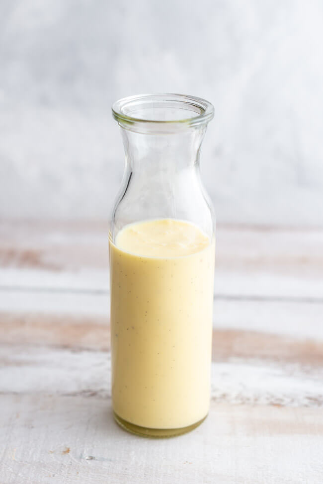 Vanillesauce in Glaskaraffe auf hellem Untergrund.
