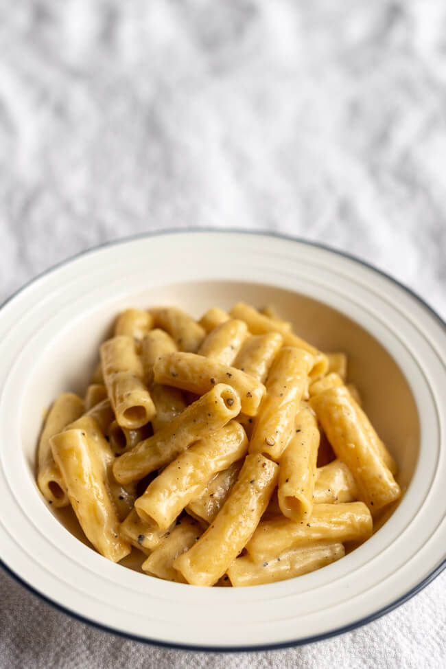 Rigatoni Cacio e Pepe auf weißem Pastateller.