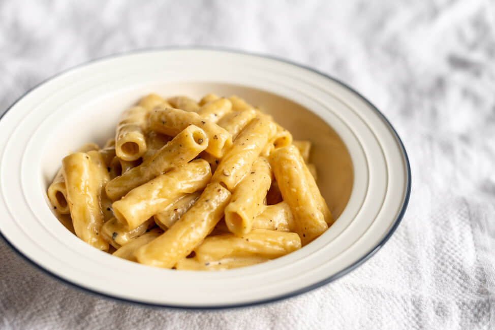 Rigatoni Cacio e Pepe auf weißem Pastateller.