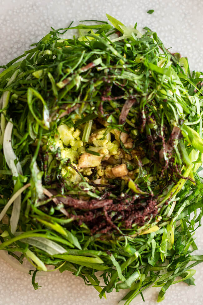 Türkischer Eiersalat mit Sauerampfer-Kräutersalat angerichtet auf weißem Teller auf hellem Untergrund.