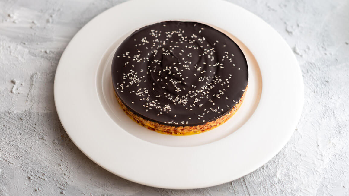 Power Cake, glasiert mit dunkler Schokolade auf weißem Teller und hellem Untergrund.