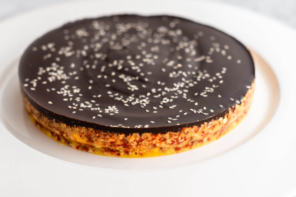 Power Cake, glasiert mit dunkler Schokolade auf weißem Teller und hellem Untergrund.