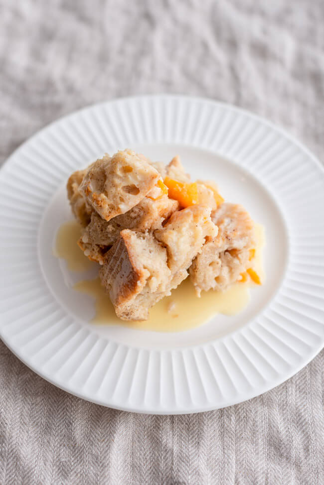 Bread Pudding mit Rumsoße auf weißem Teller.