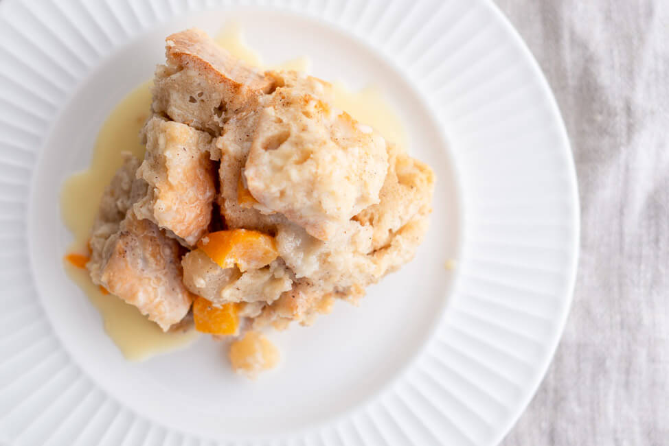 Bread Pudding mit Rumsoße auf weißem Teller.