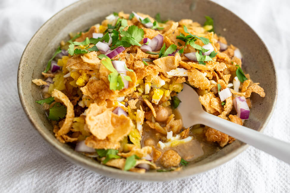 Chotpoti mit weißem Löffel in grauem Teller.
