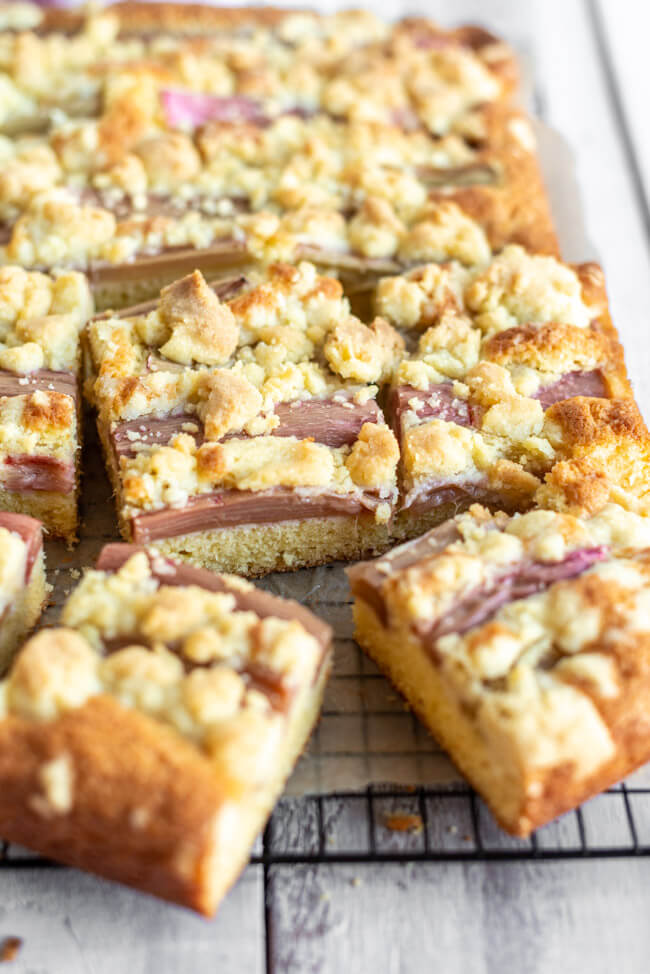 Rhabarber Streuselkuchen in Form eines Blechkuchen auf schwarzem Kuchengitter. #rhabarbersaison #rhabarber #rhabarberkuchen