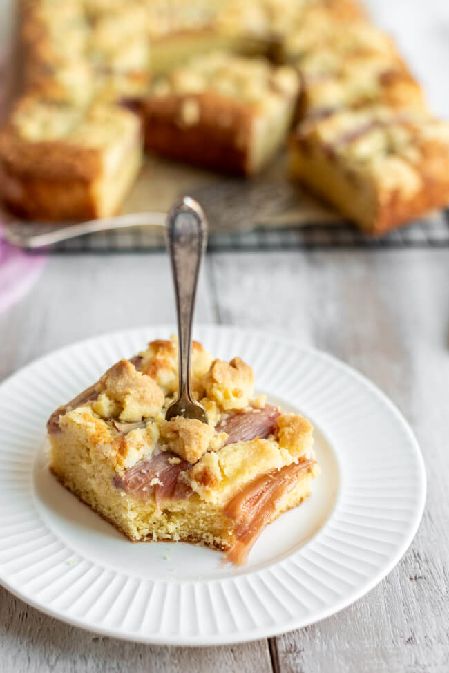 Ein Stück Rhabarber Streuselkuchen auf weißem Porzellanteller. #rhabarbersaison #rhabarber #rhabarberkuchen