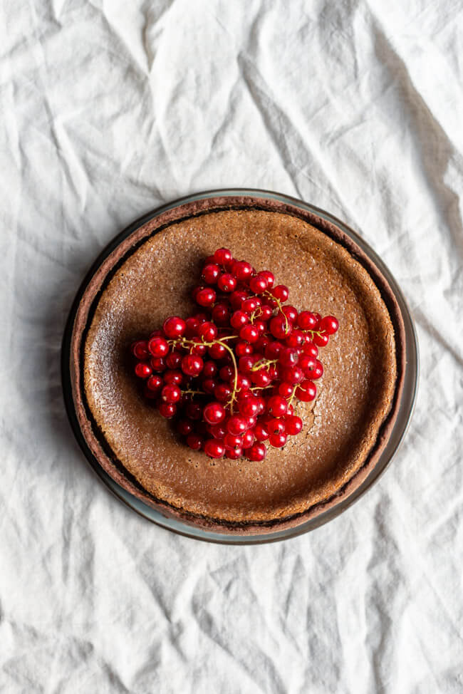 Nougatkäsekuchen dekoriert mit frischen Johannisbeeren im auf heller Tischdecke.