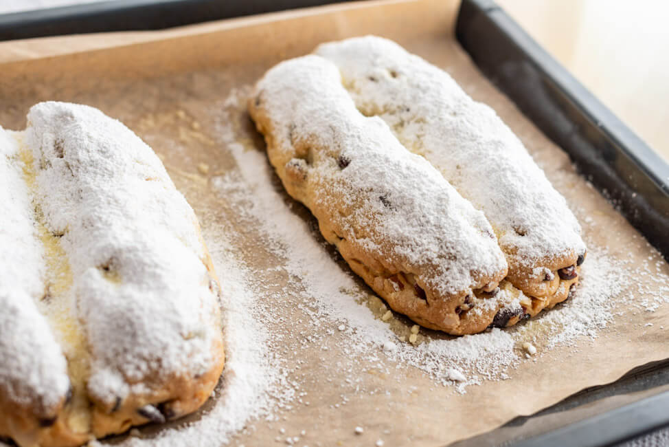 Marzipanstollen mit Cranberries auf Backblech frisch bestäubt mit Puderzucker.