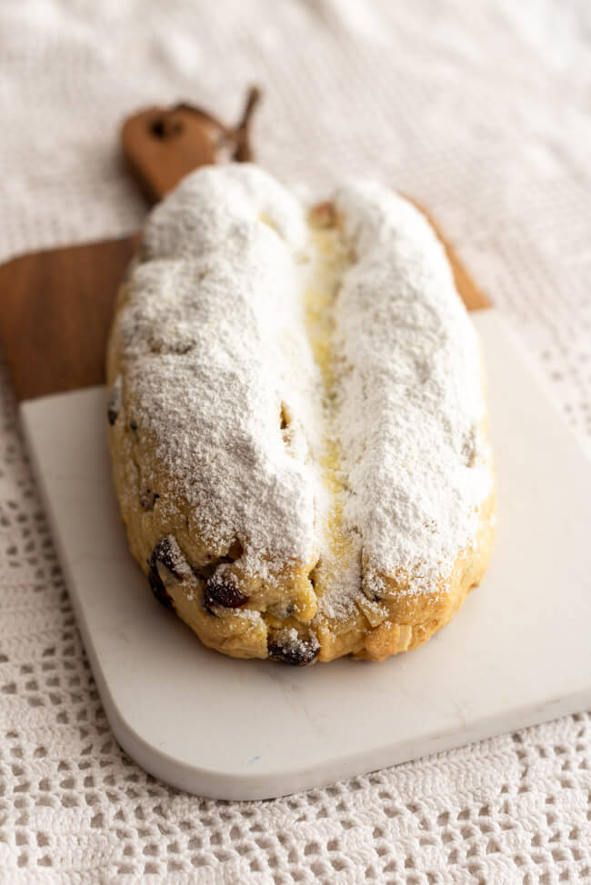 Marzipanstollen mit Cranberries auf Marmorbrett und weißem Untergrund.