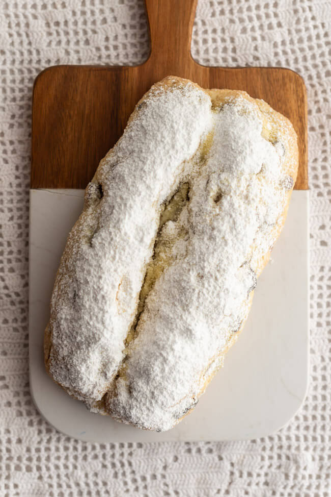 Marzipanstollen mit Cranberries auf Marmorbrett und weißem Untergrund.