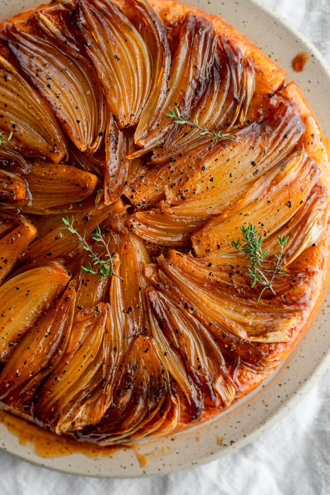 Zwiebeltarte auf Tonteller und weißem Tischtuch.