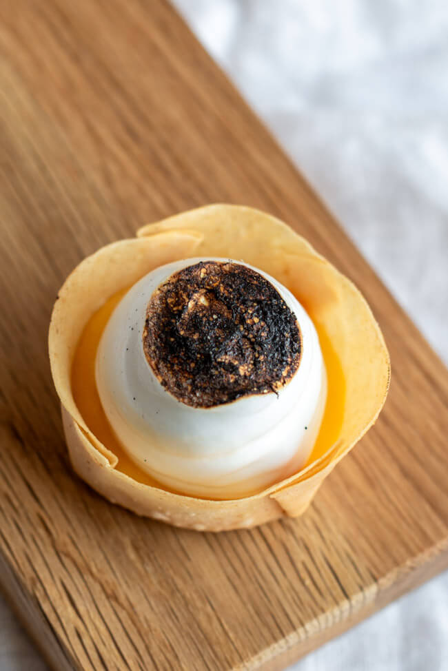 Yuzu Tarte auf Holzbrett und weißem Untergrund.