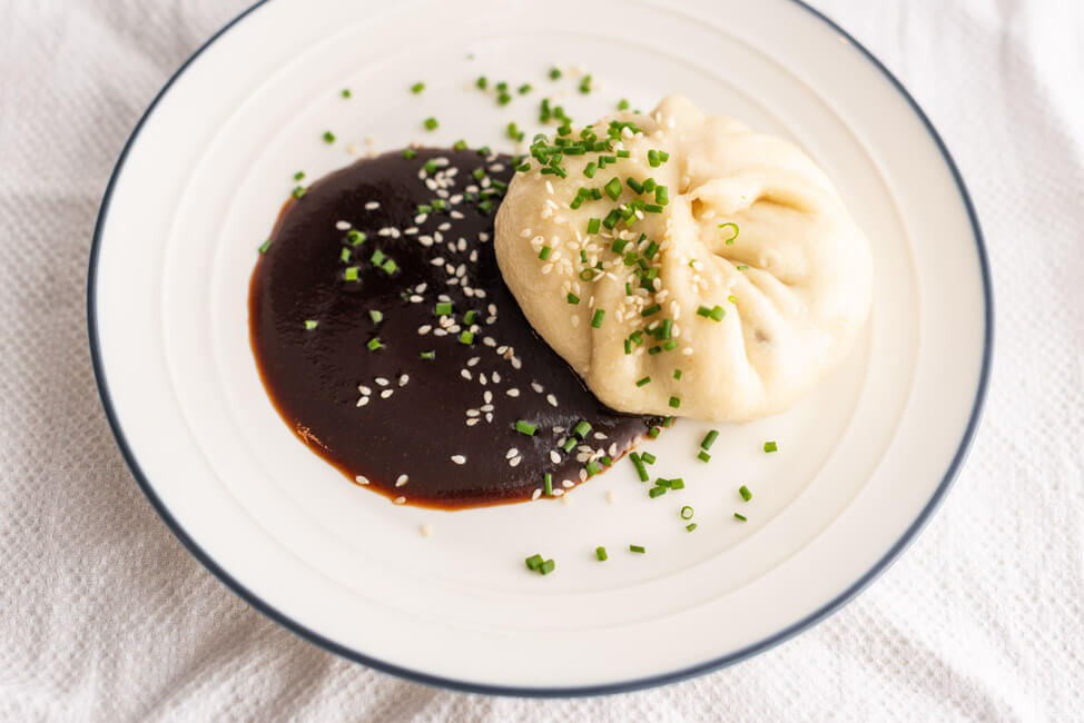 Chinesische Baozi aus Kitchen Impossible, gefüllt mit Pack Choi und Shitake Pilzen mit Dumpling Sauce auf Tonteller.