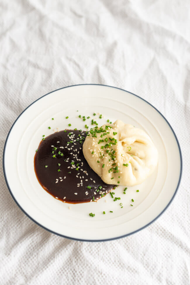 Chinesische Baozi aus Kitchen Impossible, gefüllt mit Pack Choi und Shitake Pilzen mit Dumpling Sauce auf Tonteller.