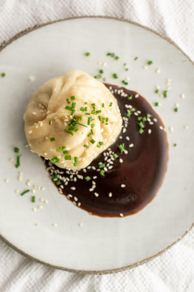Chinesische Baozi aus Kitchen Impossible, gefüllt mit Pack Choi und Shitake Pilzen mit Dumpling Sauce auf Tonteller.